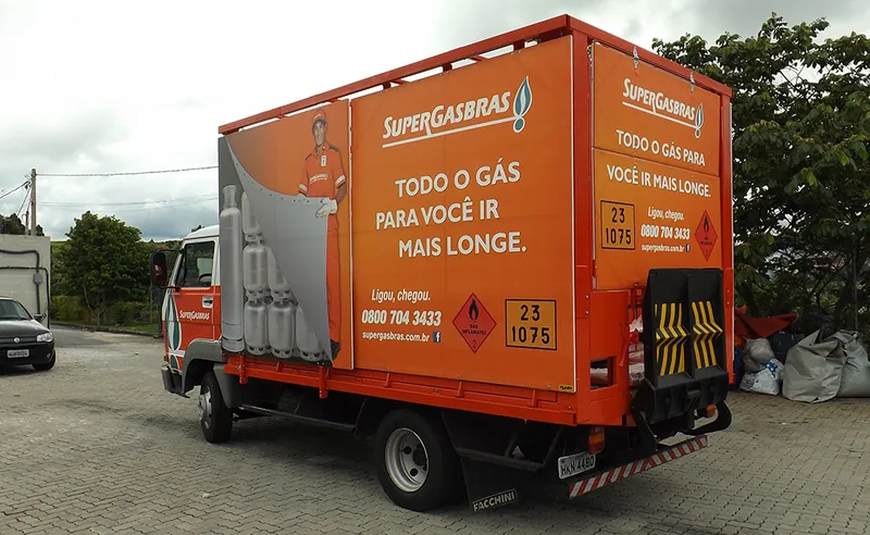 Caminhão laranja com painel de alumínio e lona da Supergasbrás