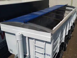 Caçamba com lona azul enrolada sobre a borda e arcos de sustentação