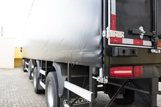 Traseira de carreta com lona cinza e lanternas vermelhas