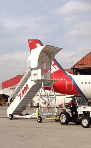 Escada de avião com cobertura de lona ao lado de uma aeronave da TAM